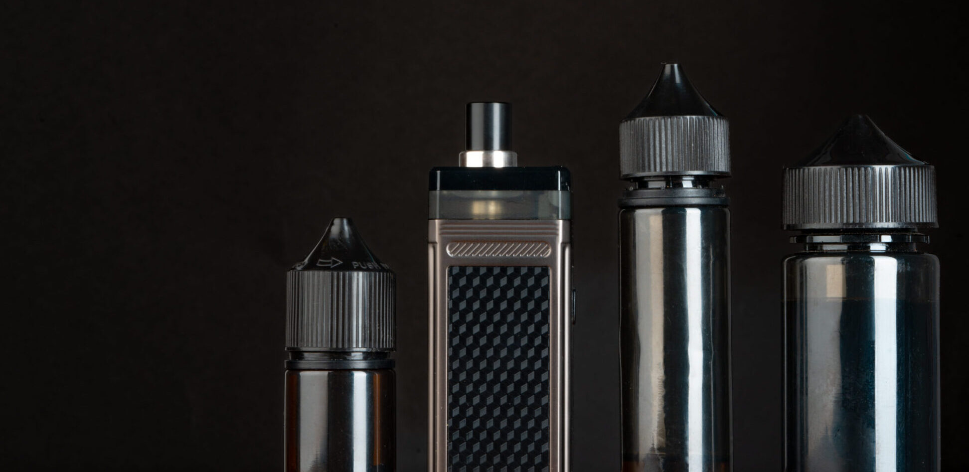 Vape and vape liquid bottles against black background